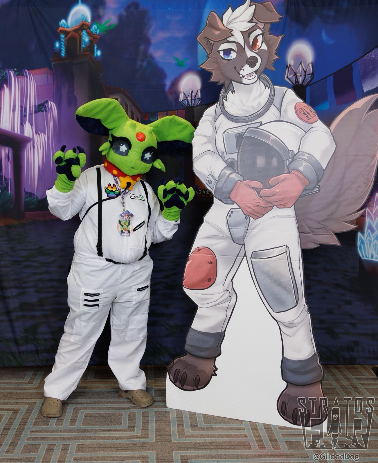 A photograph of the Cosmo fursuit taken at Stratosfur 2024 by Gilded Dog Photography. Cosmo is a green Espeon wearing a bell collar and a space suit.